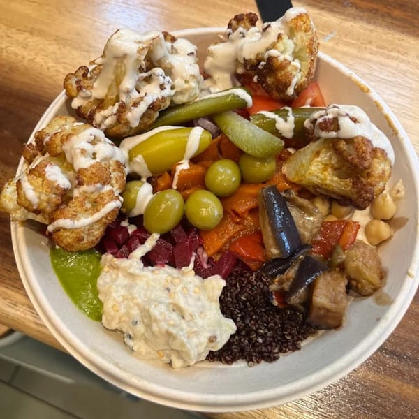 A colorful kosher bowl from Moshe's Falafel with roasted cauliflower, pickles, olives, and various salads.